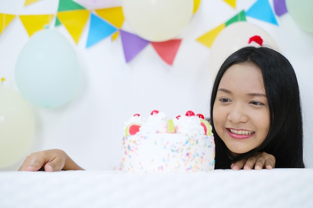 Chica joven feliz con pastel en la fiesta de cumpleaños sobre fondo blanco.