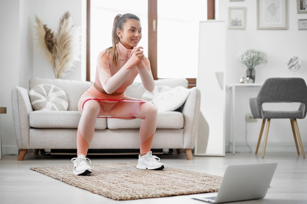 Chica joven fitness haciendo ejercicios deportivos en su sala de estar en casa