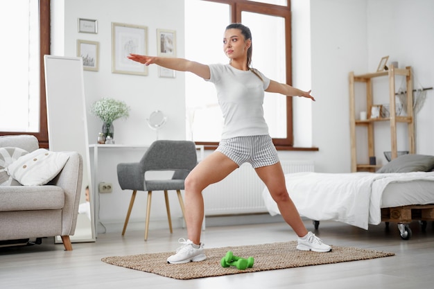 Chica joven fitness haciendo ejercicios deportivos en su sala de estar en casa