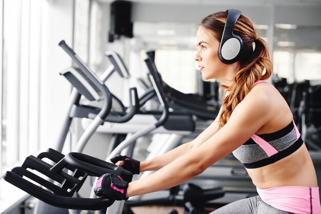 Chica joven fitness haciendo ejercicios en la máquina en el gimnasio