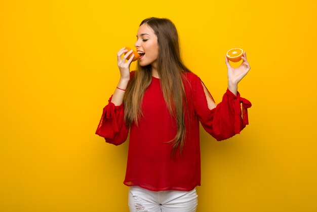 Foto chica joven en fondo amarillo vibrante con las naranjas