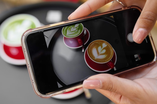 Chica joven con fotografía de teléfono inteligente de café latte art en cámara móvil