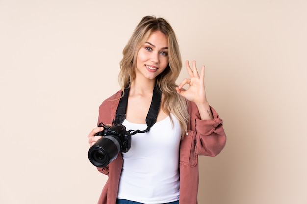 Chica joven fotógrafo sobre pared mostrando signo bien con los dedos