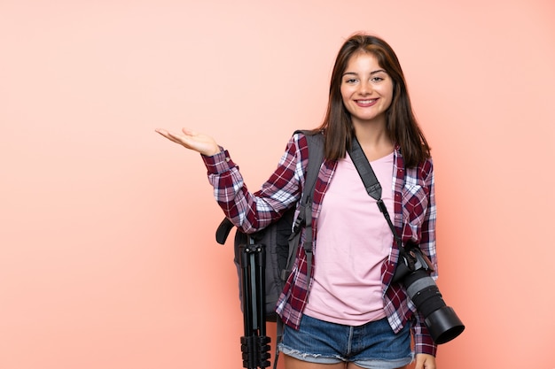 Chica joven fotógrafo sobre pared rosa aislado con copyspace imaginario en la palma