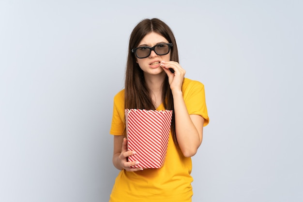 Chica joven con gafas 3d y sosteniendo un gran cubo de palomitas de maíz