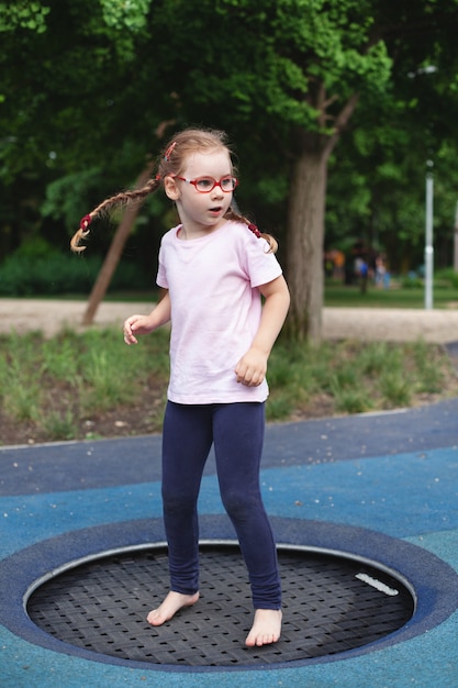 Chica joven con gafas va a practicar deportes en el patio de recreo. descanso e infancia al aire libre