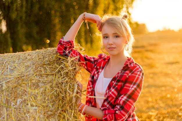 Chica joven en gavillas de paja en un campo.