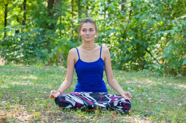 Chica joven haciendo yoga en el parque sobre la hierba