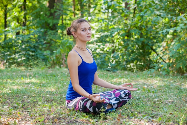 Chica joven haciendo yoga en el parque sobre la hierba