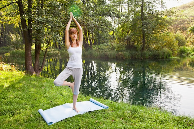 Chica joven haciendo yoga en el parque