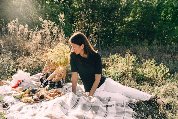 Chica joven hermosa en una comida campestre en un día de verano.