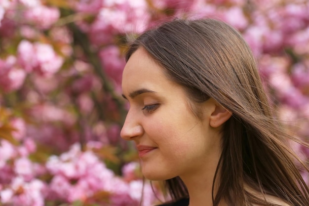 Chica joven hermosa feliz en el parque de flores