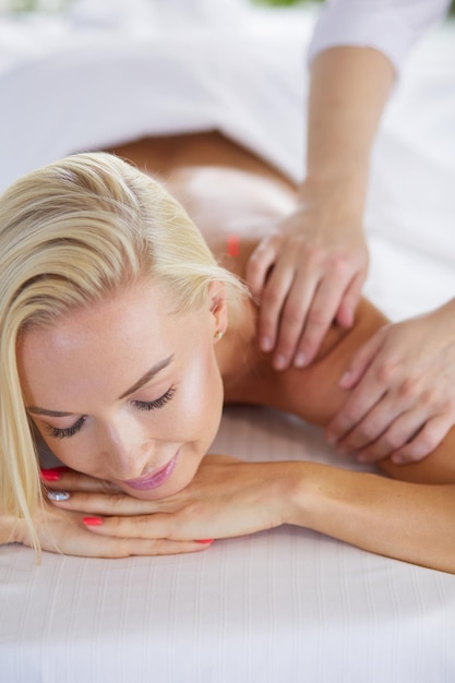 Chica joven y hermosa que se relaja en el salón de spa con terapia de masaje durante la temporada de verano o primavera backgr