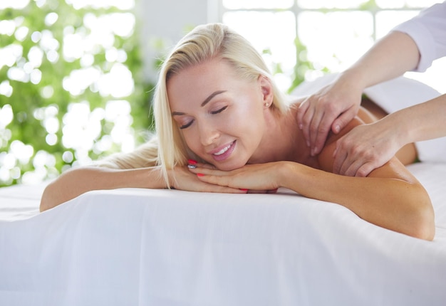 Chica joven y hermosa que se relaja en el salón de spa con terapia de masaje durante la temporada de verano o primavera backgr