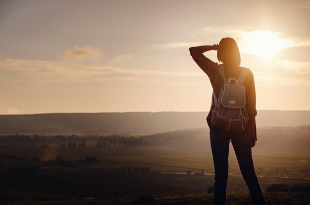 Chica joven inconformista disfruta del atardecer en el mirador Mujer de viaje con mochila