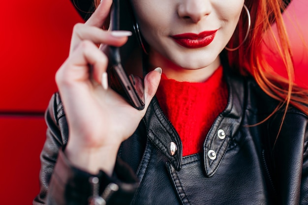 Chica joven inconformista con estilo con el pelo rojo hablando por teléfono