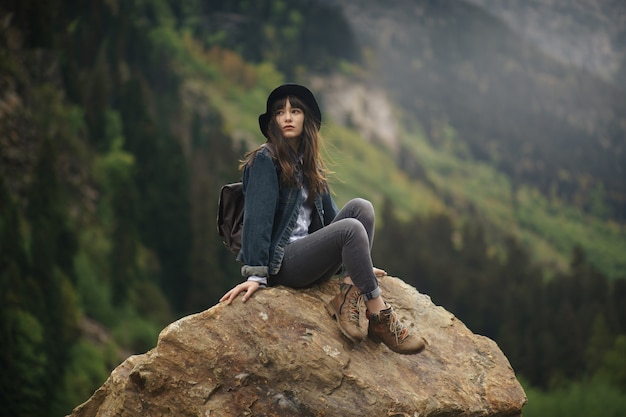 Chica joven inconformista con mochila disfrutando del atardecer en la cima de la montaña. Viajero turístico en maqueta de vista de paisaje de valle de fondo. Excursionista en busca de la luz del sol destello en viaje