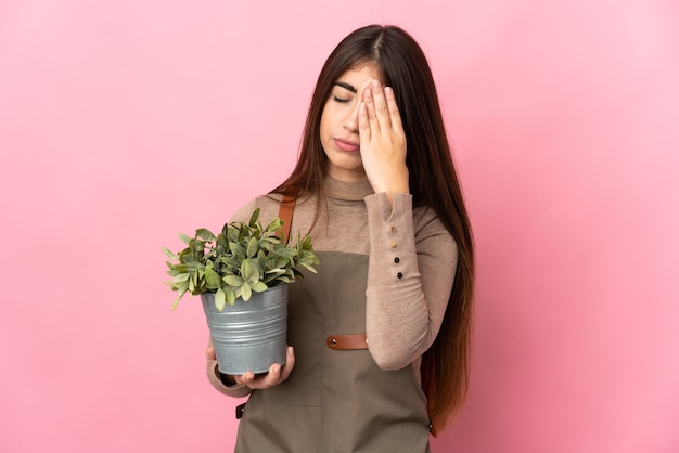 Chica joven jardinero sosteniendo una planta aislada