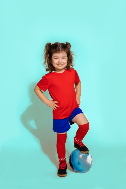 Chica joven jugador de fútbol de pie 5-6 años sosteniendo el fútbol con el pie