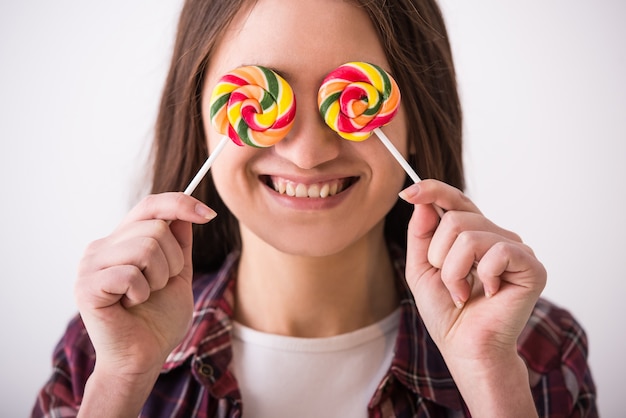 Chica joven juguetona hermosa con dos lollipops coloridos.