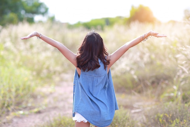 Foto chica joven y linda que tiene un momento feliz y enoying entre campo de hierba en la naturaleza