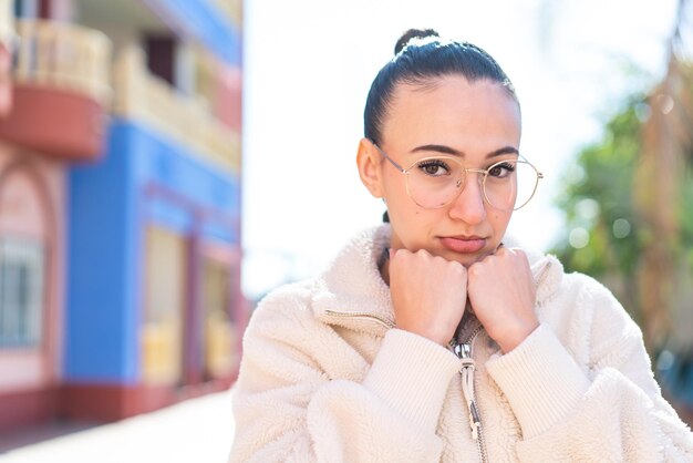 Chica joven marroquí al aire libre con gafas y cansado