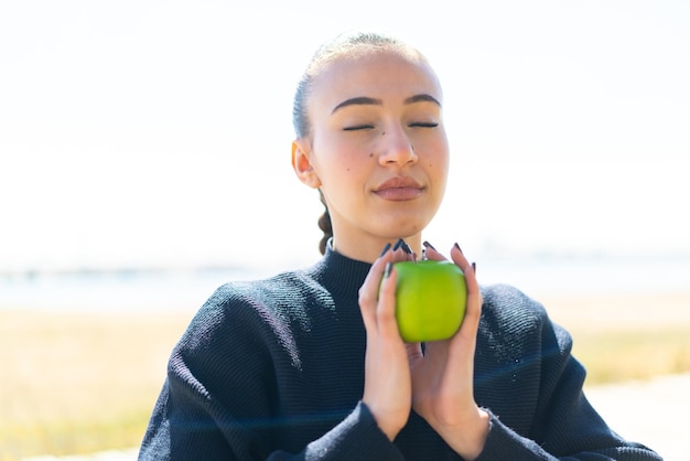 Chica joven marroquí al aire libre sosteniendo una manzana