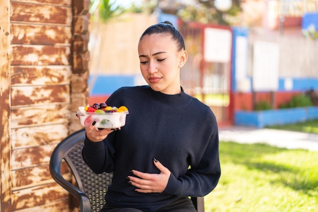 Chica joven marroquí sosteniendo un plato de fruta al aire libre