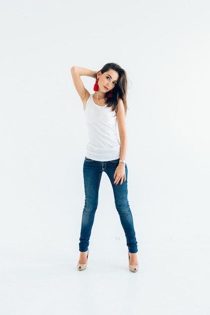 Chica joven modelo en una camiseta blanca y pantalones de mezclilla