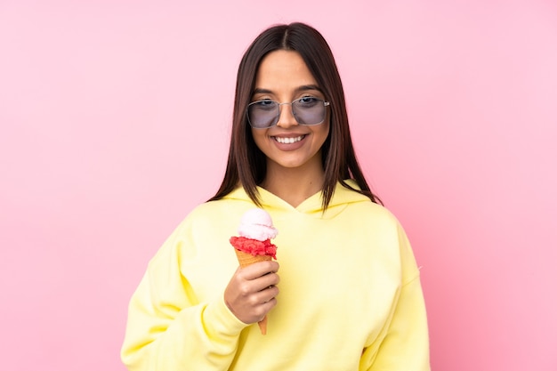 Chica joven morena sosteniendo un helado de cucurucho aislado