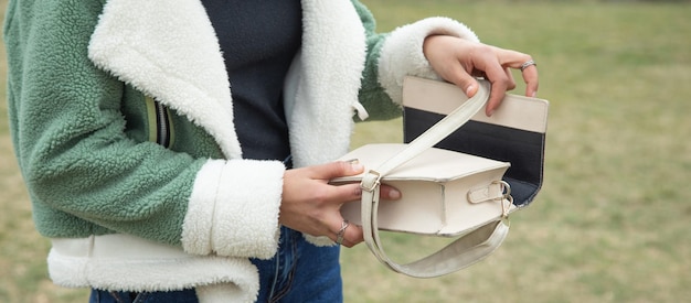 Una chica joven mostrando un bolso al aire libre