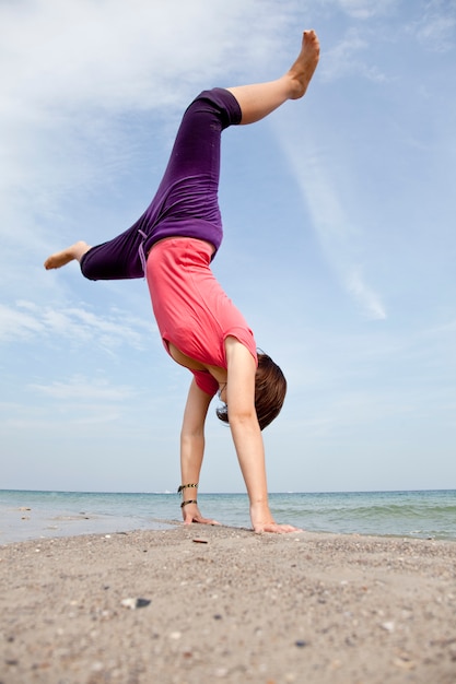 Chica joven muestra un acrobático en la playa.