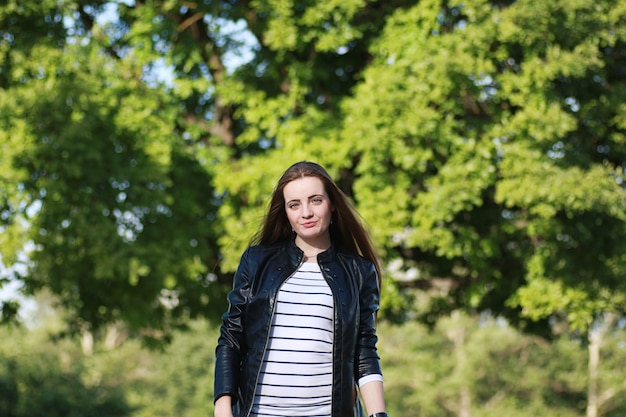 Chica joven en un paseo. Chica con una chaqueta de cuero en la calle. Hermosa chica en el parque.