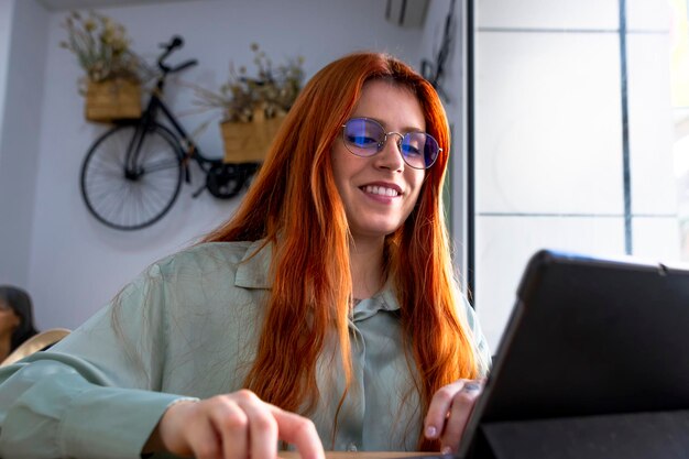 Chica joven pelirroja feliz con gafas de teletrabajo en el bar