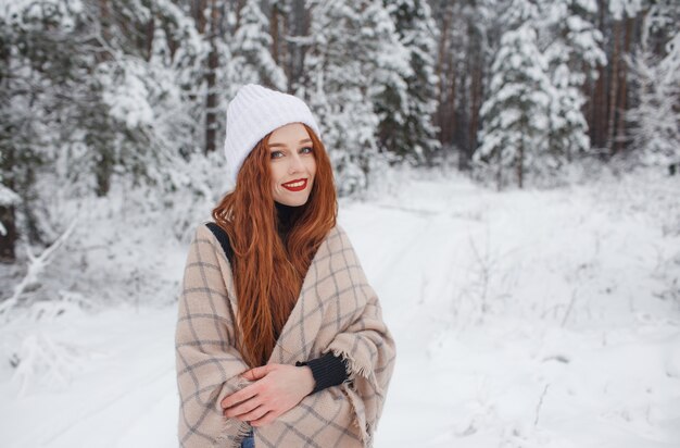 Chica joven con pelo largo rojo en un paisaje de invierno.