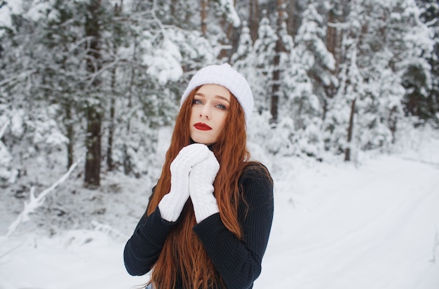 Chica joven con pelo largo rojo en un paisaje de invierno.