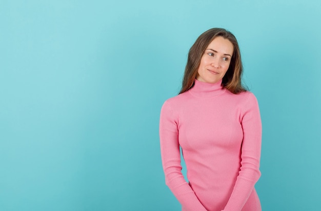 Chica joven pensativa está mirando a la derecha sobre fondo azul.