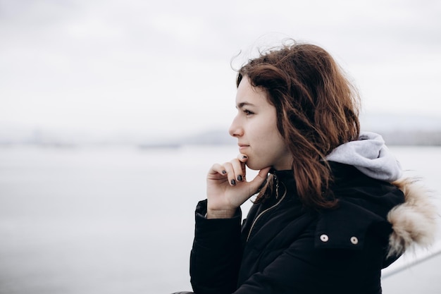 Chica joven pensativa mirando al mar desde el barco Chica adolescente en el ferry Frío mar gris