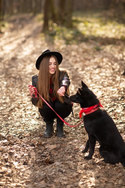 Chica joven con un perro que camina en el parque del otoño