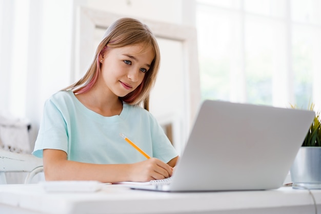 Chica joven con portátil para la tarea en casa