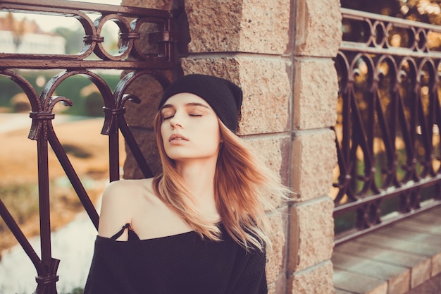 Foto chica joven posando en una barandilla de un puente