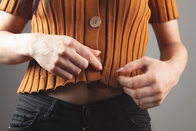 Chica joven posando en un suéter corto en jeans