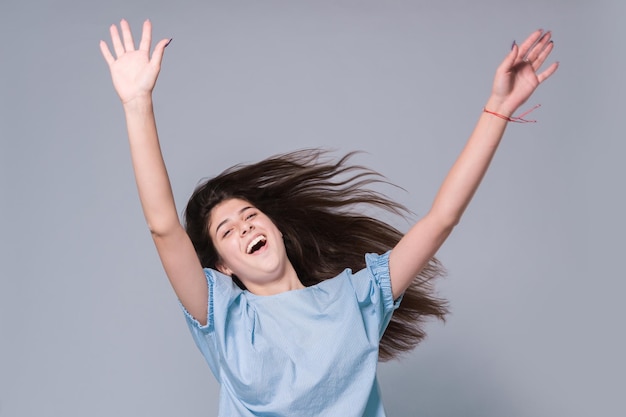 Chica joven positiva con los brazos extendidos hacia arriba en un salto