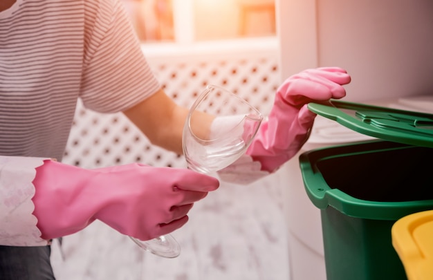 Chica joven que clasifica la basura en la cocina.