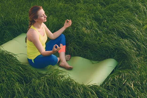 Chica joven que hace yoga en el patio trasero