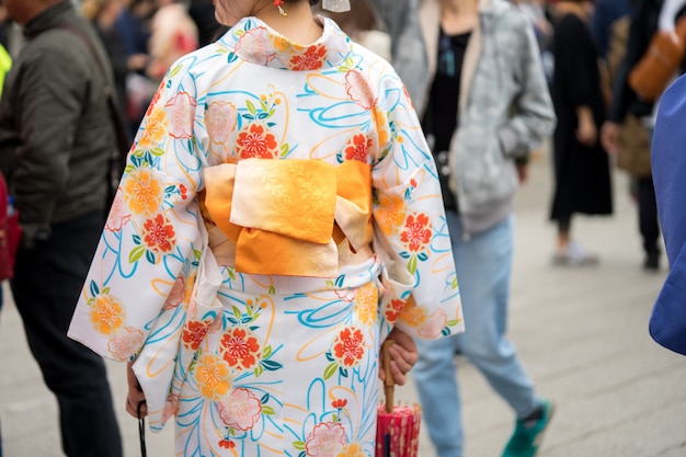 Chica joven que lleva el kimono japonés que se coloca delante del templo de sensoji en tokio, japón.