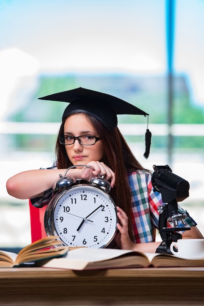 Chica joven que se prepara para los exámenes con el reloj grande