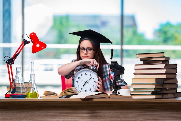 Chica joven que se prepara para los exámenes con el reloj grande