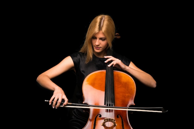 Chica joven que toca el violoncelo en fondo negro aislado