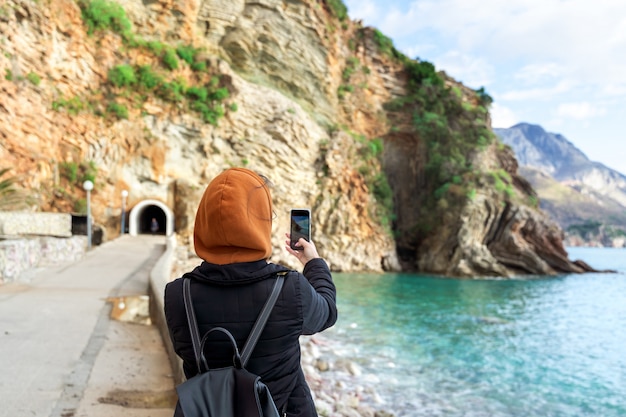 Chica joven que toma fotos del paisaje con el teléfono inteligente móvil